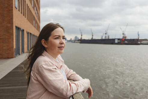 Lächelnde junge Frau im Hamburger Hafen stehend - IHF00959