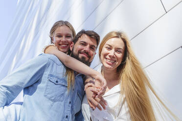 Glückliche Familie vor einer Mauer stehend - IHF00972