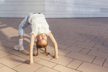 Happy girl standing in bridge position on floor - IHF01000