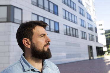 Smiling man with beard standing in front of building - IHF01006