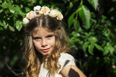 Smiling girl wearing flower crown in forest - JCMF02308