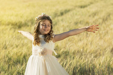 Smiling girl with arms outstretched in meadow - JCMF02309