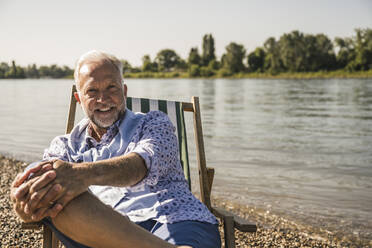 Smiling senior man at riverbank - UUF26541