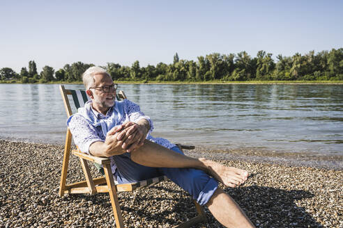 Lächelnder älterer Mann mit Brille am Flussufer - UUF26545