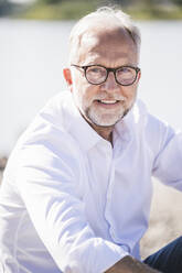 Smiling senior man wearing eyeglasses on sunny day - UUF26616