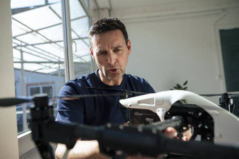 Reifer Techniker, der eine Drohne im Büro analysiert - JOSEF10645