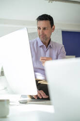 Geschäftsmann bei der Arbeit an einem Desktop-PC im Büro - JOSEF10663