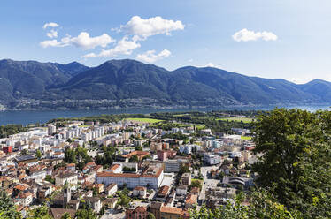 Schweiz, Tessin, Locarno, Stadthäuser mit Lago Maggiore und umliegenden Bergen im Hintergrund - GWF07466