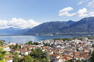 Schweiz, Tessin, Locarno, Stadthäuser mit Lago Maggiore und umliegenden Bergen im Hintergrund - GWF07467