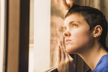 Frau mit kurzen Haaren lehnt sich zu Hause ans Fenster - MGRF00672