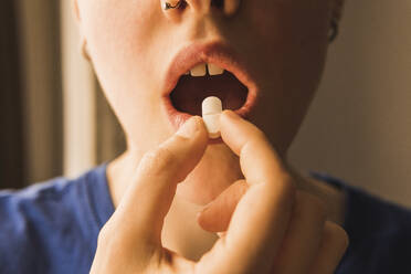 Frau mit offenem Mund nimmt Pille - MGRF00674
