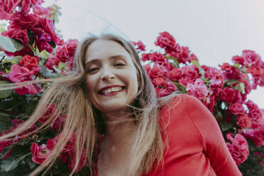 Happy woman in front of rose bush - OSF00134