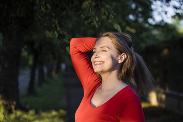 Happy woman with hand in hair enjoying sunlight - OSF00143