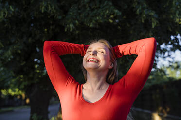 Cheerful woman with hands behind head enjoying sunlight - OSF00145