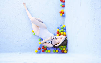 Frau liegt mit bunten Plastikbällen im leeren Schwimmbad - SVCF00104