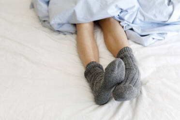 Frau mit kuscheligen Socken auf dem Bett - TYF00297