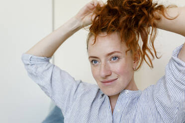 Smiling woman tying ponytail at home - TYF00299