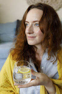 Nachdenkliche Frau mit einem Glas Sprudelwasser und einer Zitronenscheibe - TYF00311