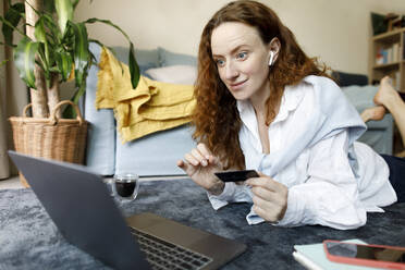 Glückliche Frau mit Kreditkarte beim Bezahlen mit dem Laptop zu Hause - TYF00313