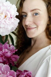 Happy beautiful woman holding pink flowers at home - TYF00341