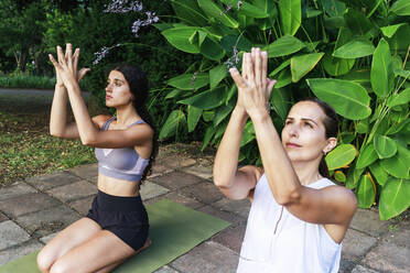 Älterer Yogatrainer mit Mädchen beim Training im Park - RFTF00247