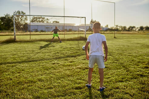 Boy standing at sports field on sunny day - ZEDF04649