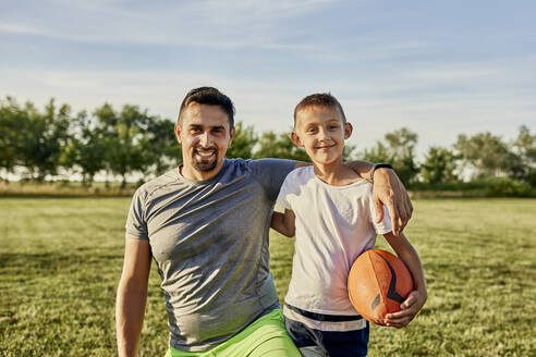 Glücklicher Vater und Sohn zusammen auf einem Sportplatz an einem sonnigen Tag - ZEDF04659
