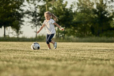 Mädchen spielt Fußball auf einem Sportplatz an einem sonnigen Tag - ZEDF04683