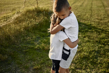 Boy hugging sister at sports field - ZEDF04690