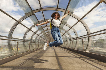 Glückliches Teenager-Mädchen, das auf der Brücke am Bahnhof Elbbrucken springt, Deutschland - IHF01024