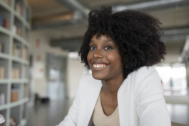 Smiling businesswoman with curly hair looking away at office - JCICF00055