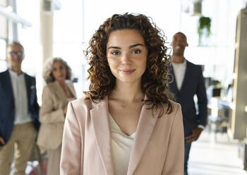 Smiling businesswoman with curly hair at office - JCICF00128