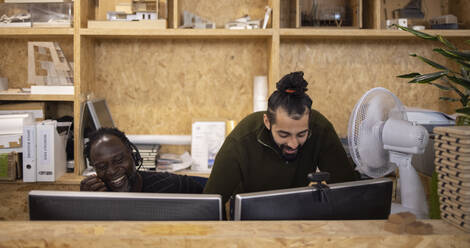 Lächelnde Geschäftsleute arbeiten an Computern im Büro - CAIF32870