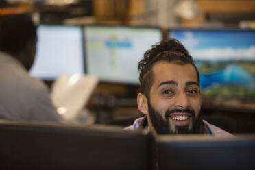 Porträt lächelnder junger Geschäftsmann bei der Arbeit im Büro - CAIF32899