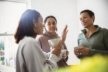 Mother and young adult daughters talking at home - CAIF32929