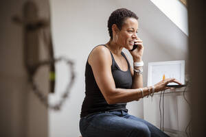 Reife Frau, die im Büro zu Hause mit einem Smartphone telefoniert - CAIF32936