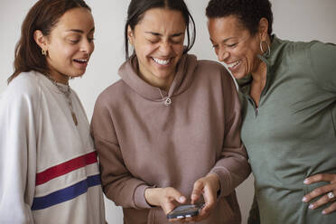 Glückliche Mutter und Töchter benutzen ein Smartphone - CAIF32964