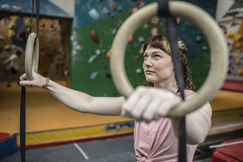 Determined young woman at gymnastics rings - CAIF32980