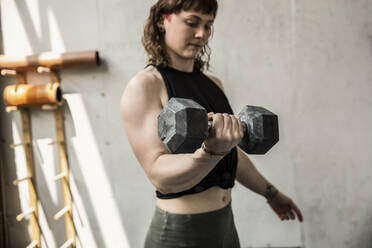 Strong young woman weight training with dumbbell - CAIF32996