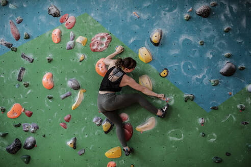 Female rock climber hanging from climbing wall - CAIF33098