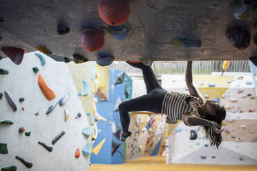 Weibliche Bergsteigerin hängt an der Kletterwand - CAIF33122