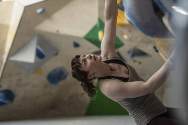 Junge Bergsteigerin schaut zur Kletterwand hinauf - CAIF33127