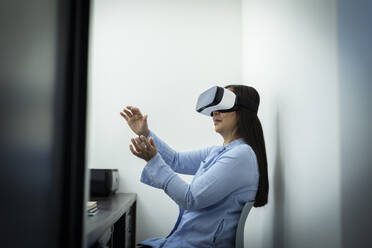 Businesswoman using VR headset in office - CAIF33248