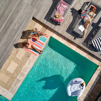 Aerial view friends relaxing at sunny summer poolside - CAIF33287