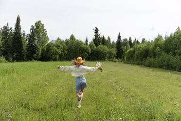 Frau mit Kamillenblüten läuft auf Gras - VBUF00134