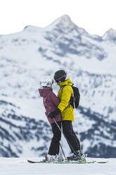 Romantisches Paar in Skikleidung umarmt sich im Skigebiet Baqueira Beret, Pyrenäen, Spanien - JAQF01039