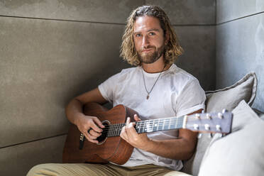 Man plucking guitar at home - DLTSF02969