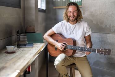 Glücklicher Mann zupft zu Hause Gitarre - DLTSF02970