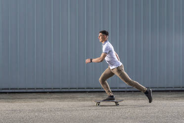 Junger Mann auf dem Skateboard vor einer Mauer - STSF03233