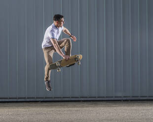 Man practicing stunt with skateboard in mid-air - STSF03235